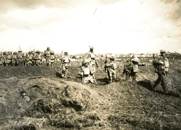 Photographie noir et blanc montrant des soldats partant à l'assaut dans une plaine.