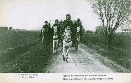Carte postale noir et blanc montrant quatre hommes à cheval tenant un fusil, sur une route de campagne.