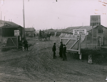 Photographie noir et blanc montrant des hommes rassemblés autour de baraquements.
