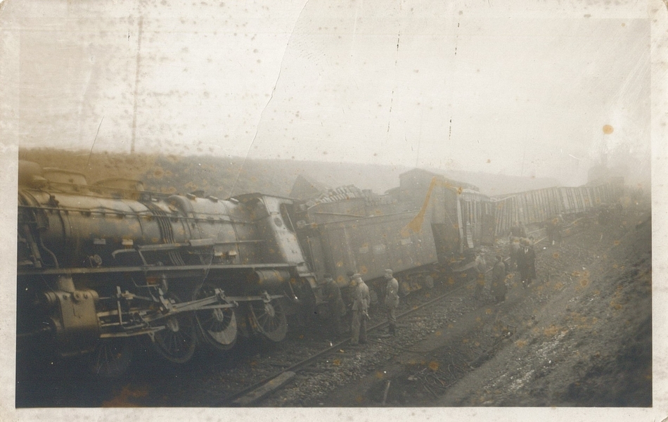 Photographie noir et blanc montrant un train déraillé avec des hommes autour.