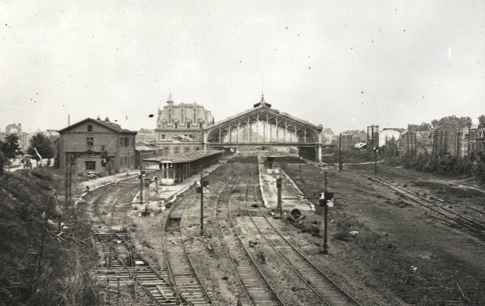 Photographie noir et blanc montrant une gare et une voie ferrée endommagés.