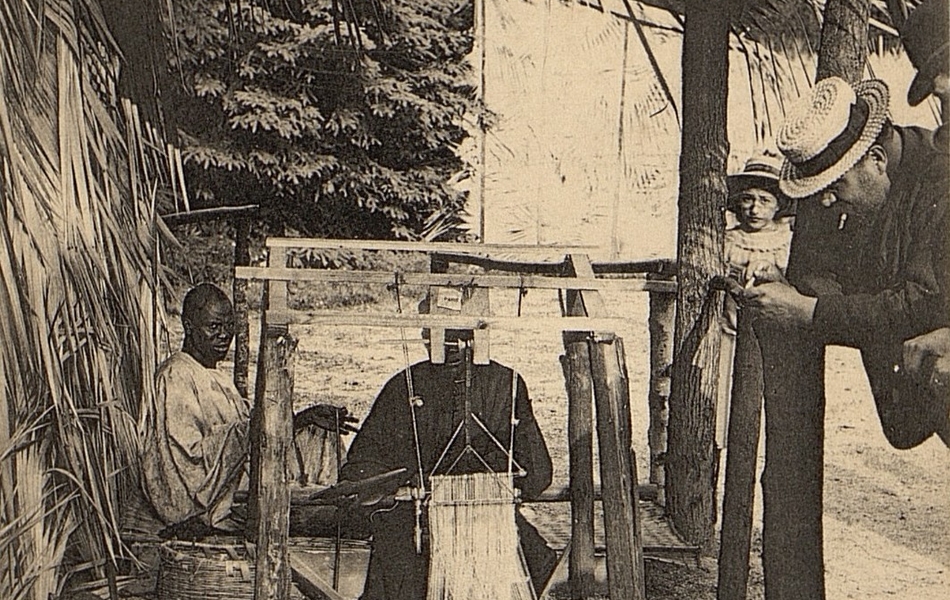 Carte postale noir et blanc montrant deux hommes assis devant un métier à tisser.