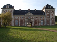 Photographie couleur montrant un grand bâtiment à porte cochère et aux fenêtres murées.