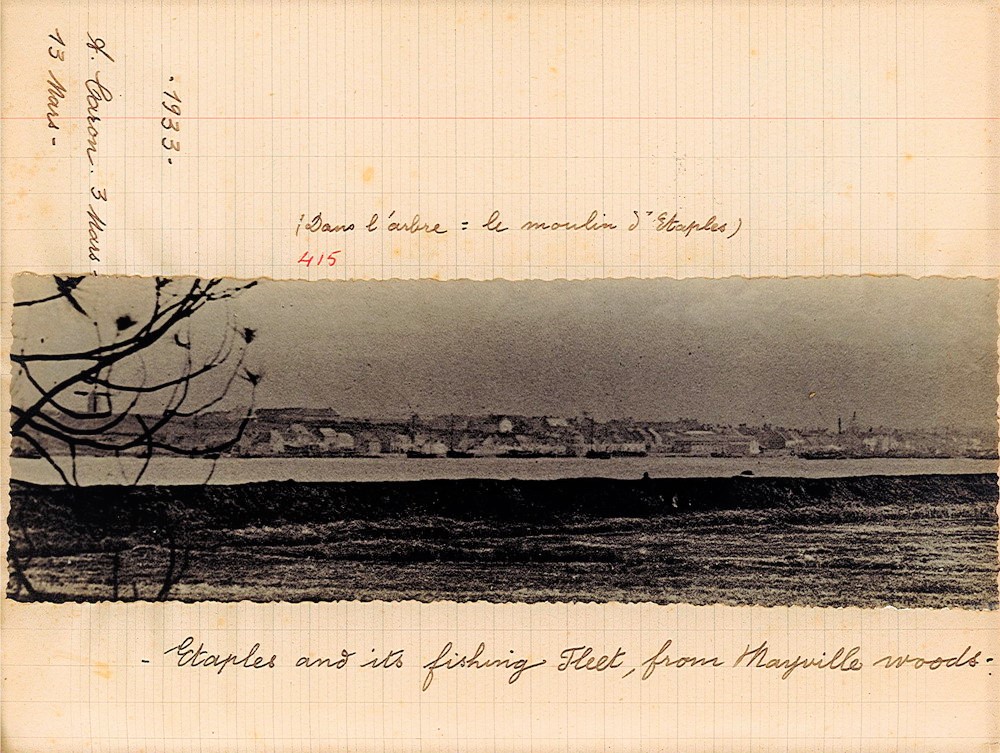 Page de cahier d'écolier sur lequel est collé une photographie noire t blanc montrant une ville en arrière plan. Autour de la photographie, la légende suivante : "Étaples and its fishing Fleet, from Mayville woods".