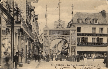 Carte postale noir et blanc d'un croisement de rues où l'on a dressé un arc de triomphe.