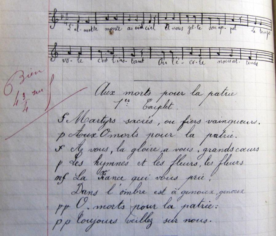 Page d'un cahier d'écolier. En haut, on voit deux portées de musique et en-dessous le texte suivant : "Aux morts pour la patrie. Premier couplet : Martyrs sacrés ou fiers vainqueurs, ô morts pour la patrie.À vous la gloire, à vous, grands coeurs, les hymnes et les fleurs, les fleurs. La France qui vous prie, dans l'ombre est à genoux, genoux. Ô morts pour la patrie, toujours veillez sur nous". En rouge, la maître a annoté : "Bien. 4 3/4 sur 5".