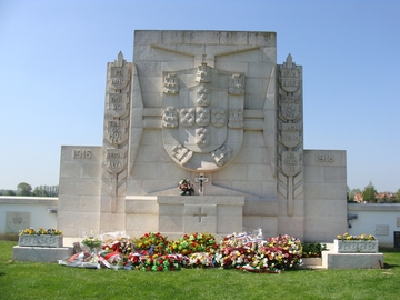 Monument aux morts en pierre blanche, fleuri.