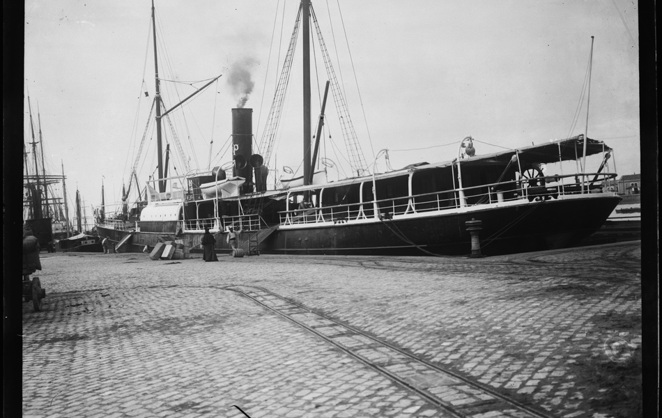 Photographie noir et blanc montrant une péniche à quai.