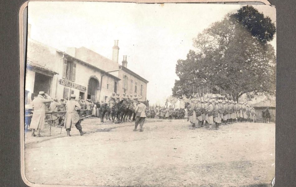 Photographie représentant des militaires réalisant une prise d'arme dans un village.