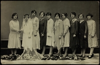 Photographie noir et blanc d'un groupe de 10 femmes debout et alignées dont une en tenue de mariée posant pour le photographe.