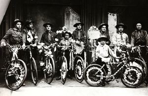 Photographie noir et blanc montrant e jeunes scouts tenant des vélos recouverts de rubans.