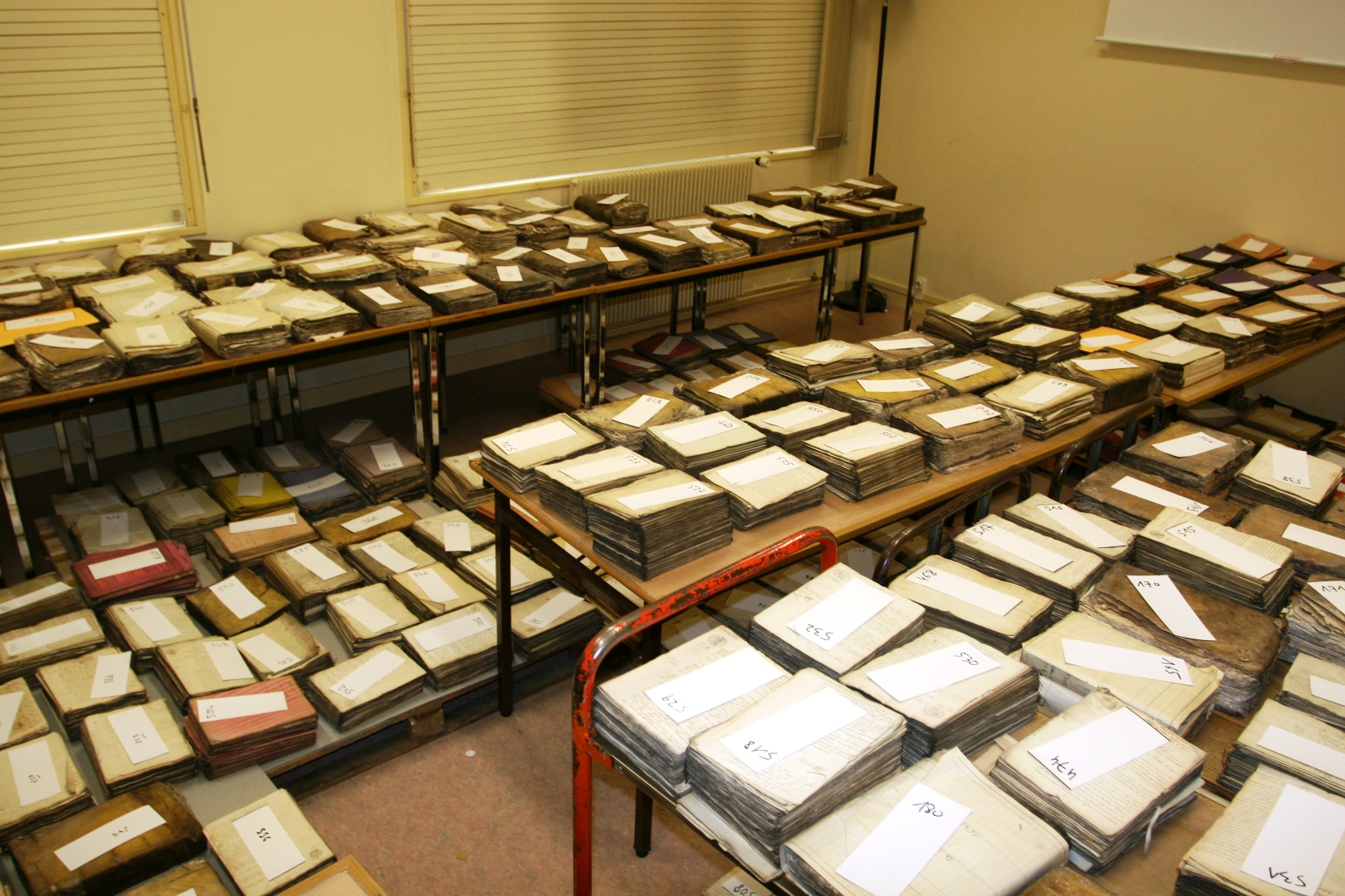 Photographie couleur montrant des tas de dossiers occupant toute une pièce.