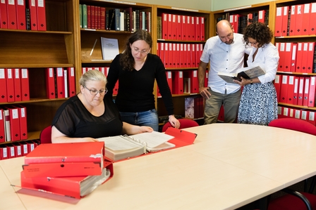 Photographie couleur montrant des personnes faisant des recherches dans des inventaires.